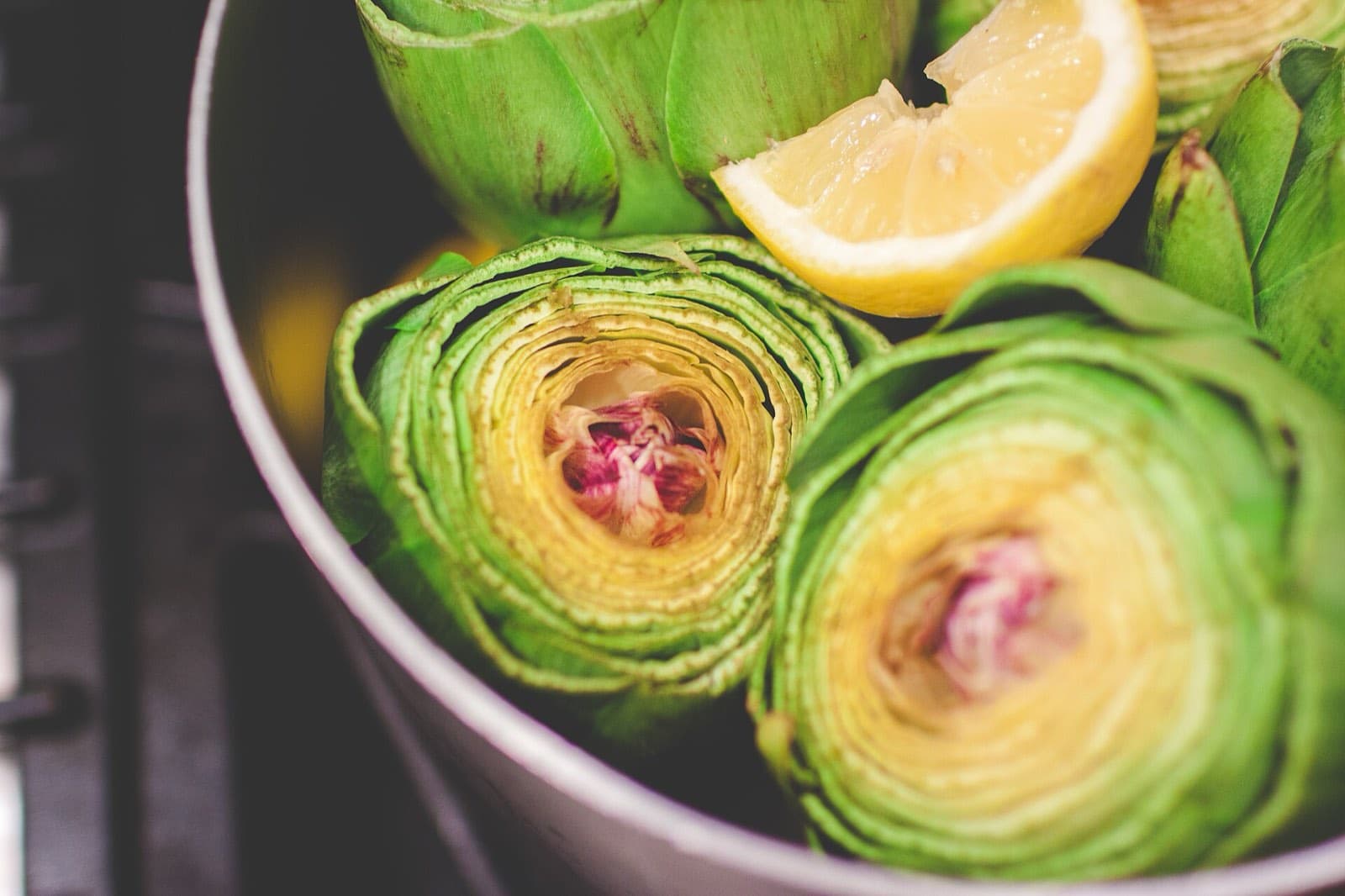 Halved artichokes with lemon in a bowl