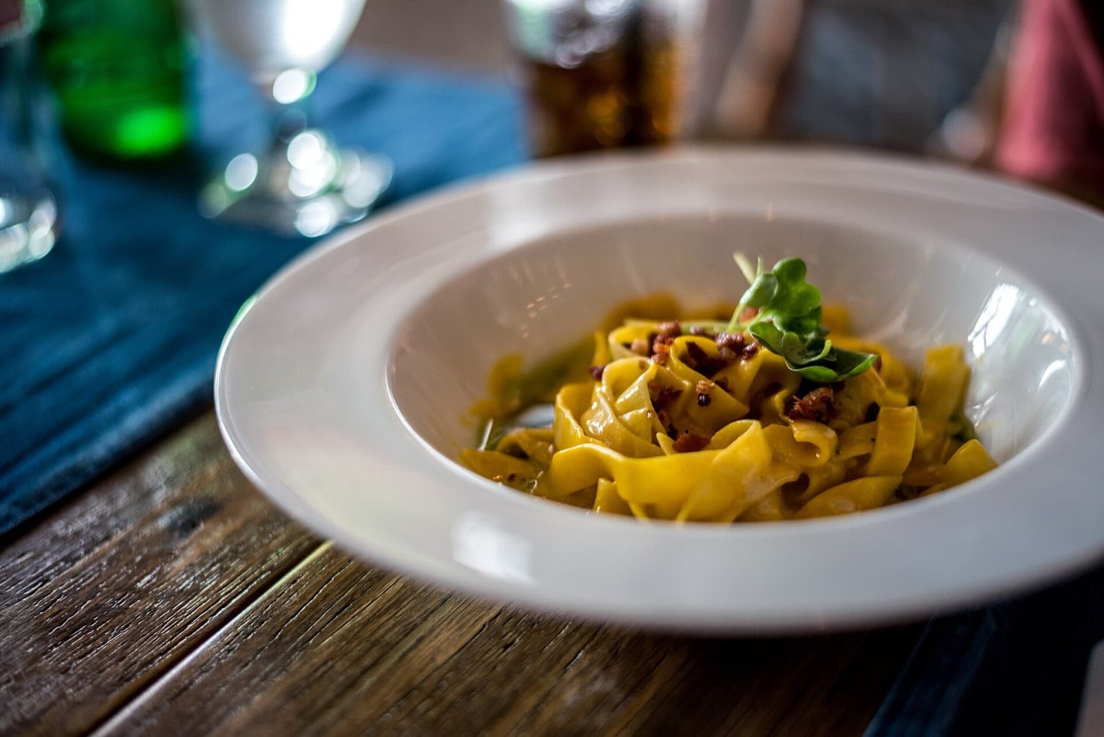 Tagliatelle in a wide white bowl on a dark wooden table