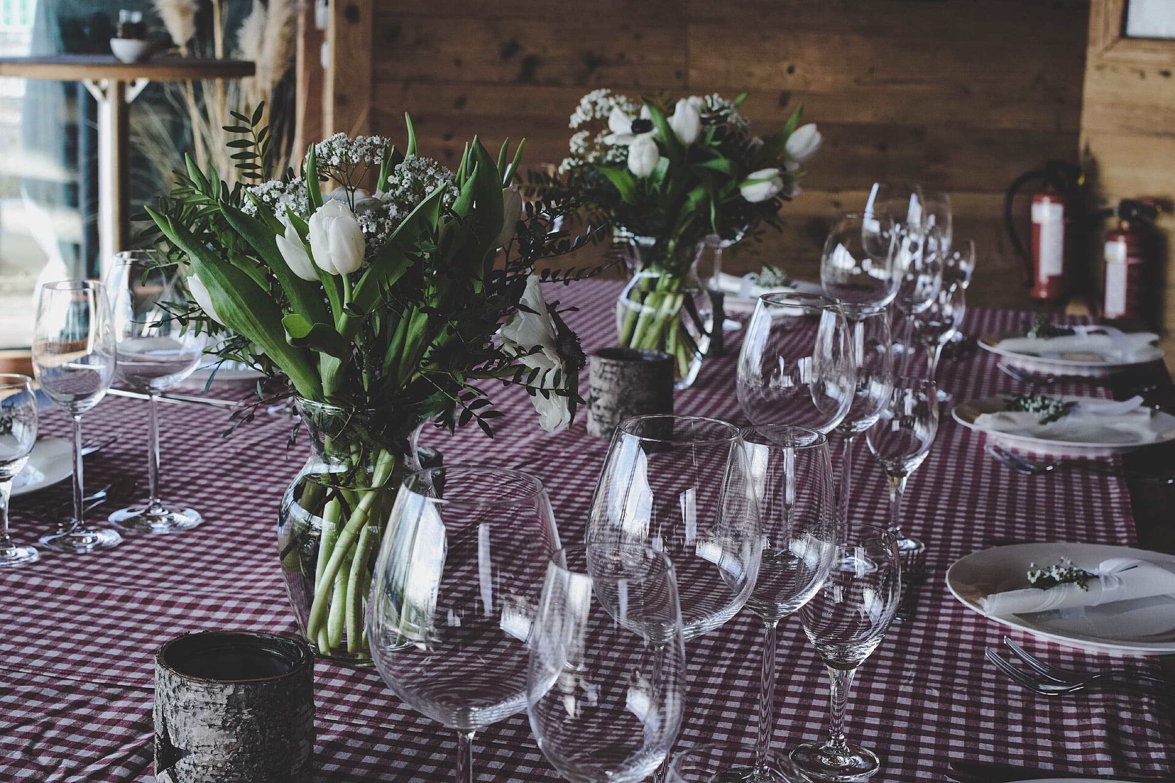A long table dressed with flowers and rows of wine glasses