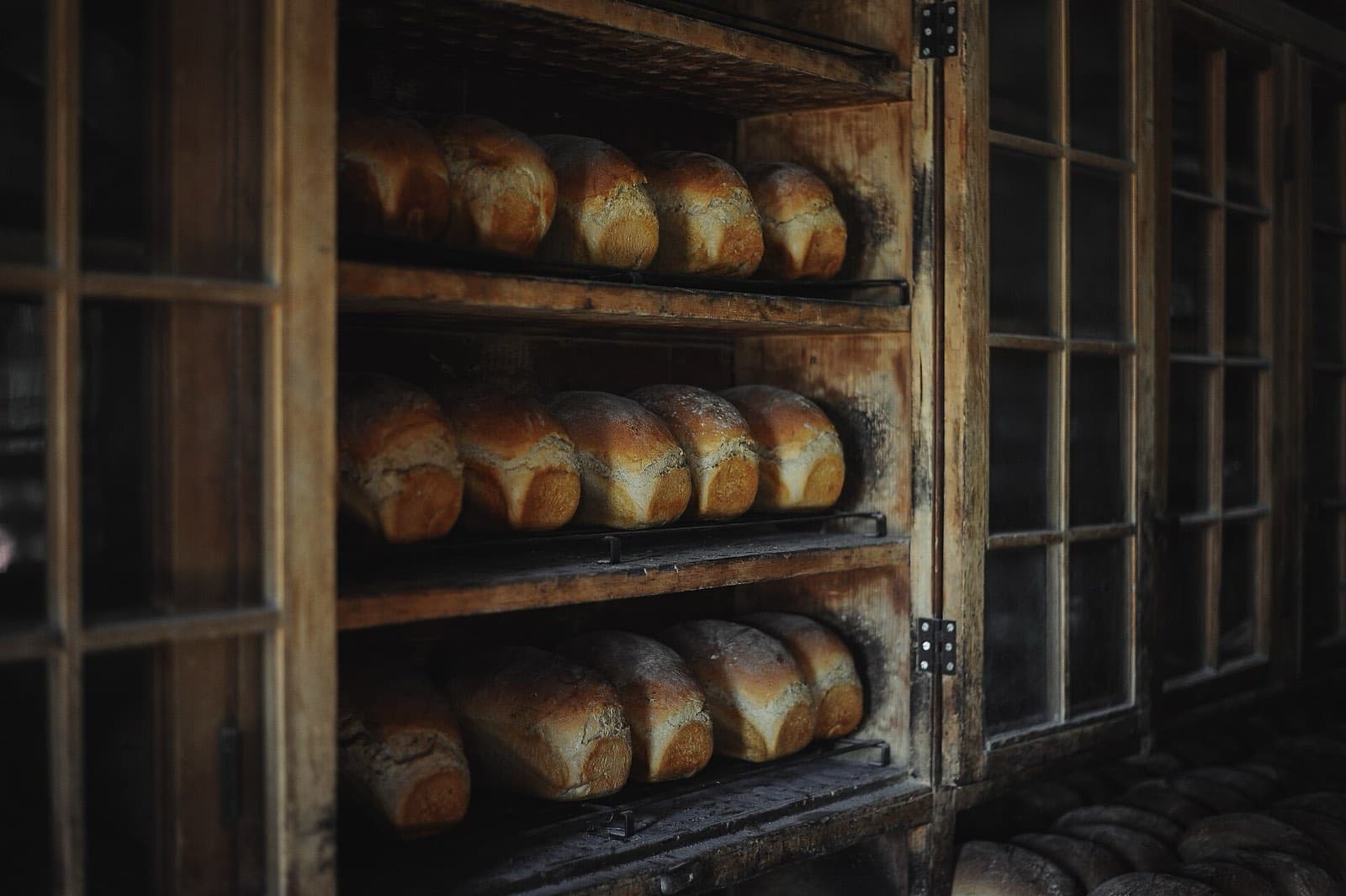 Loaves of bread resting on wooden bakery shelves