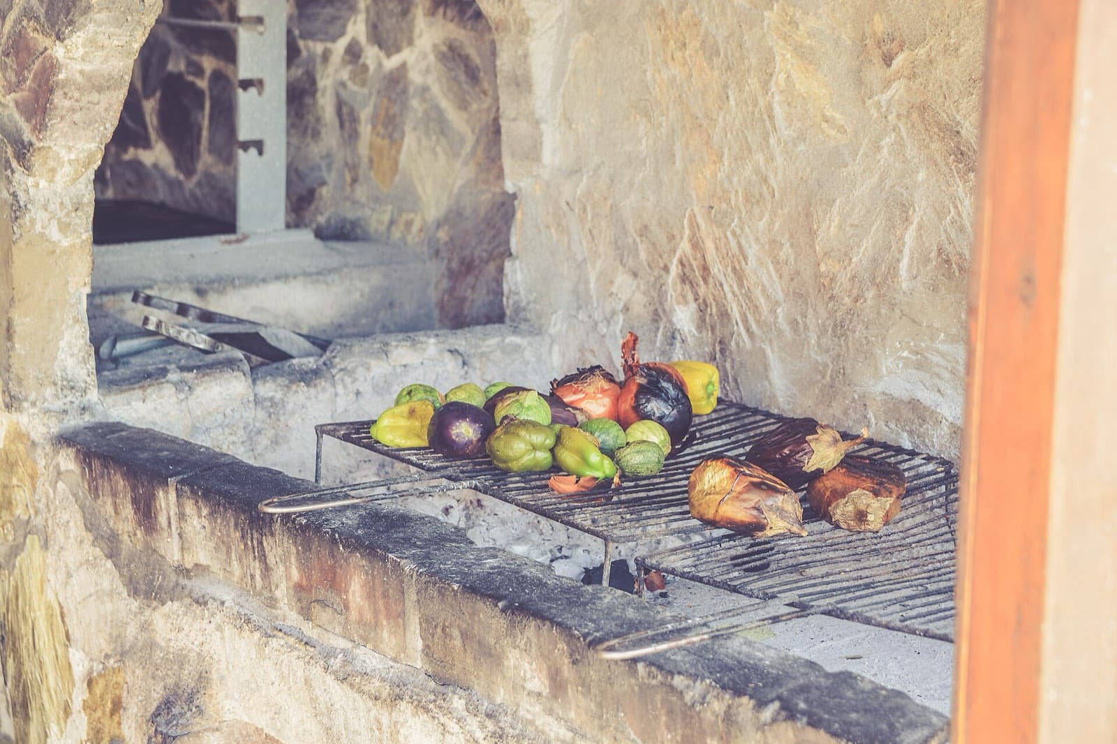 Vegetables charring on a grill inside a stone hearth