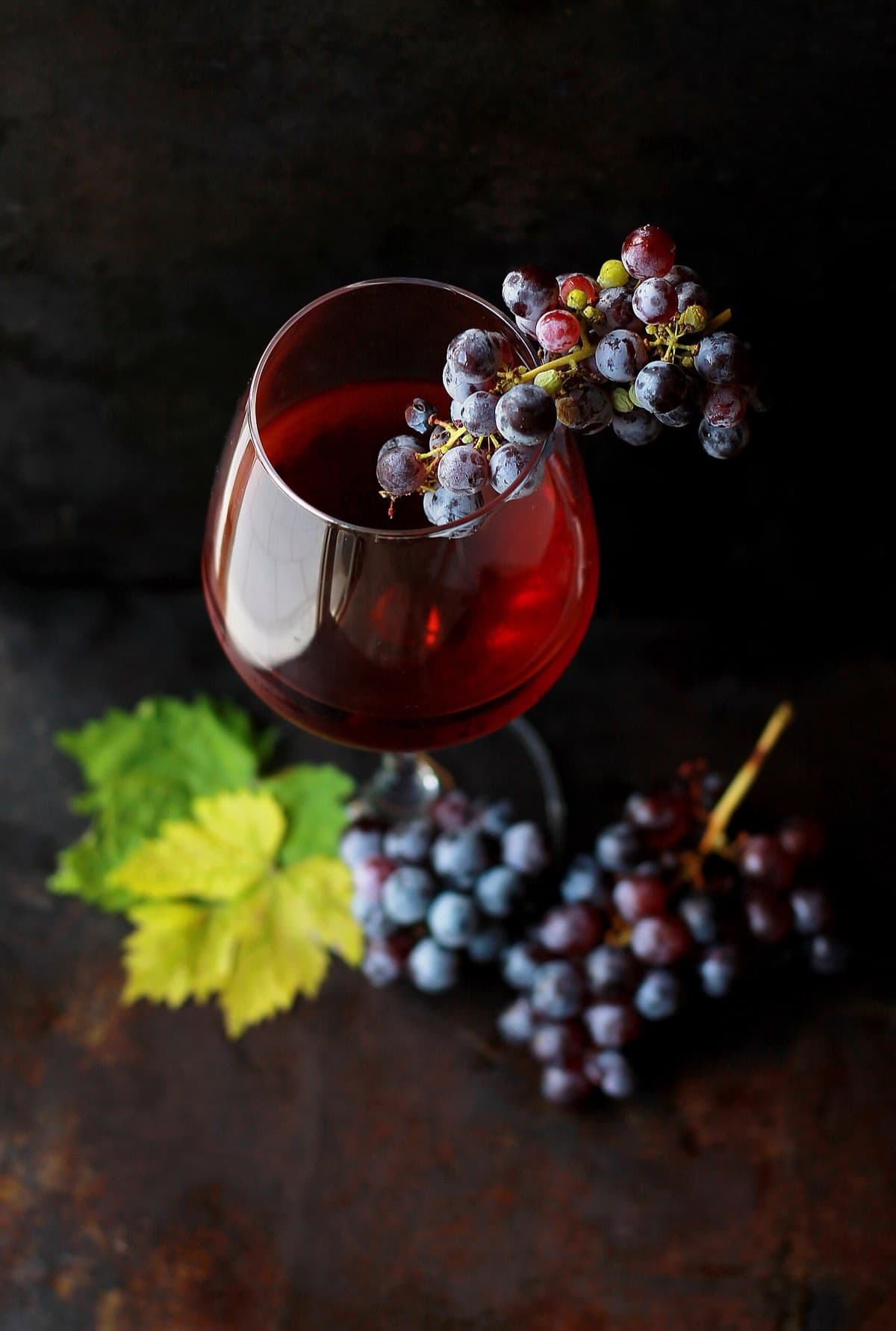 A glass of red wine beside a bunch of dark grapes