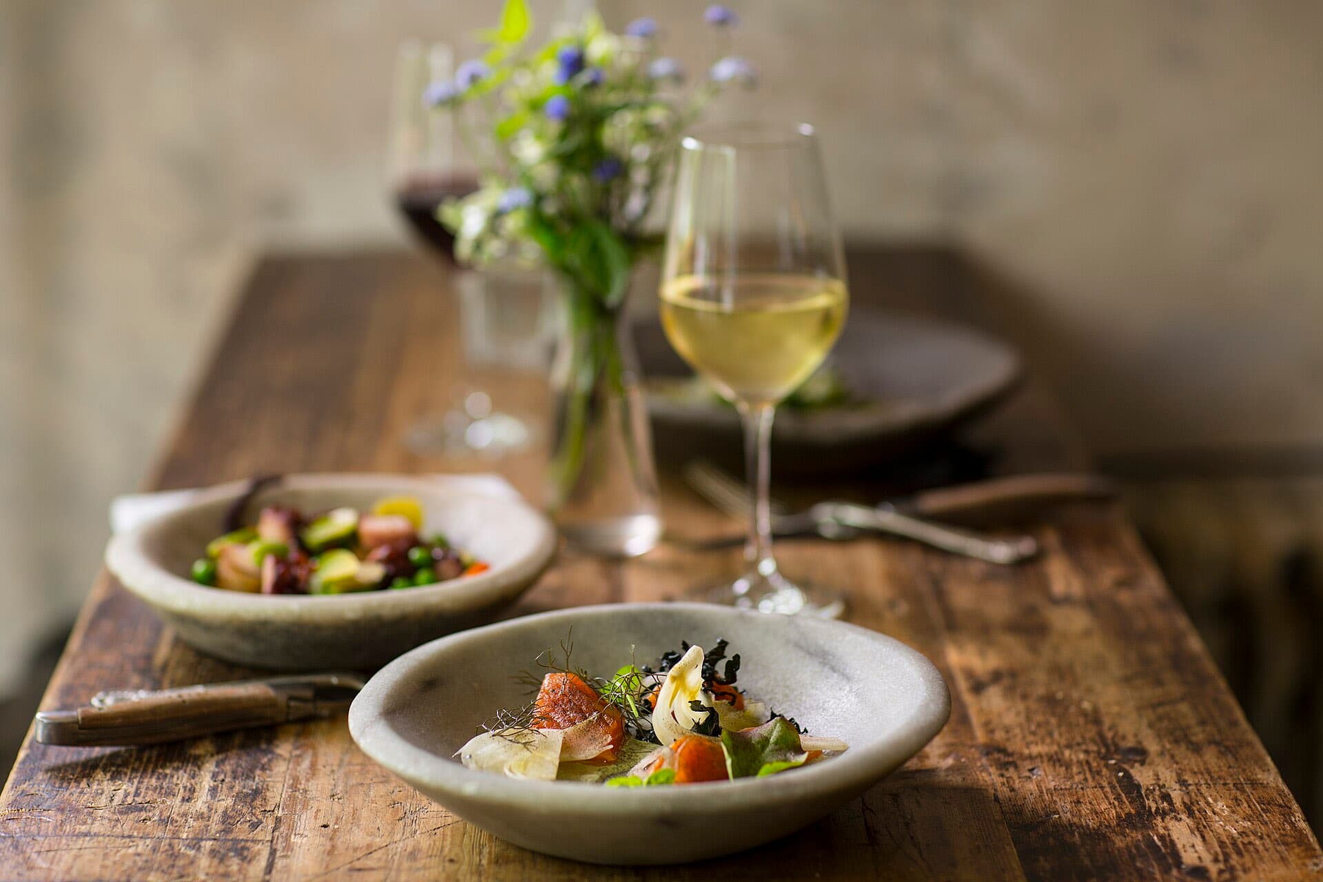 Small plates and a glass of white wine on a rustic wooden table