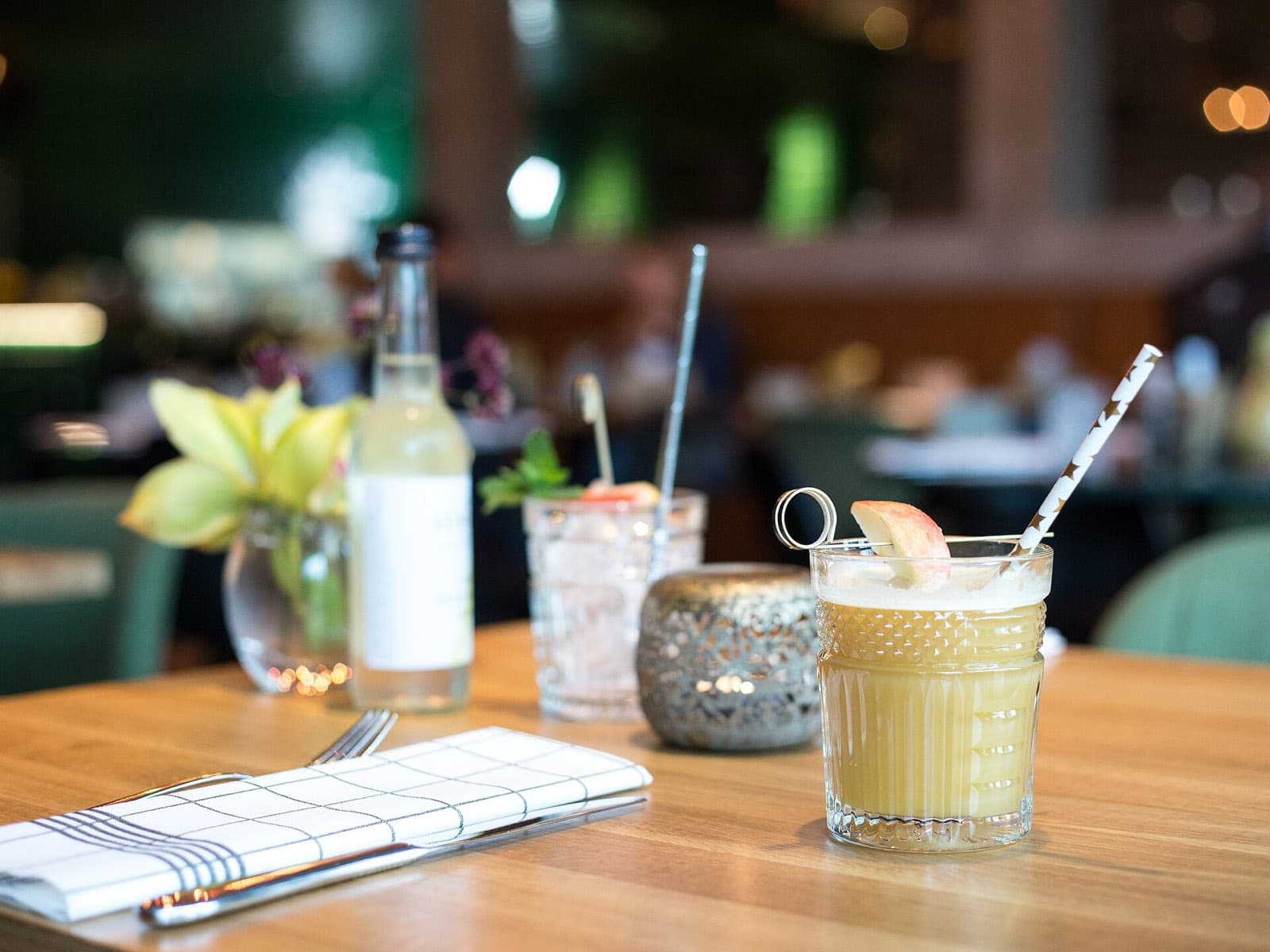 A cocktail, a bottle and a candle on a restaurant table