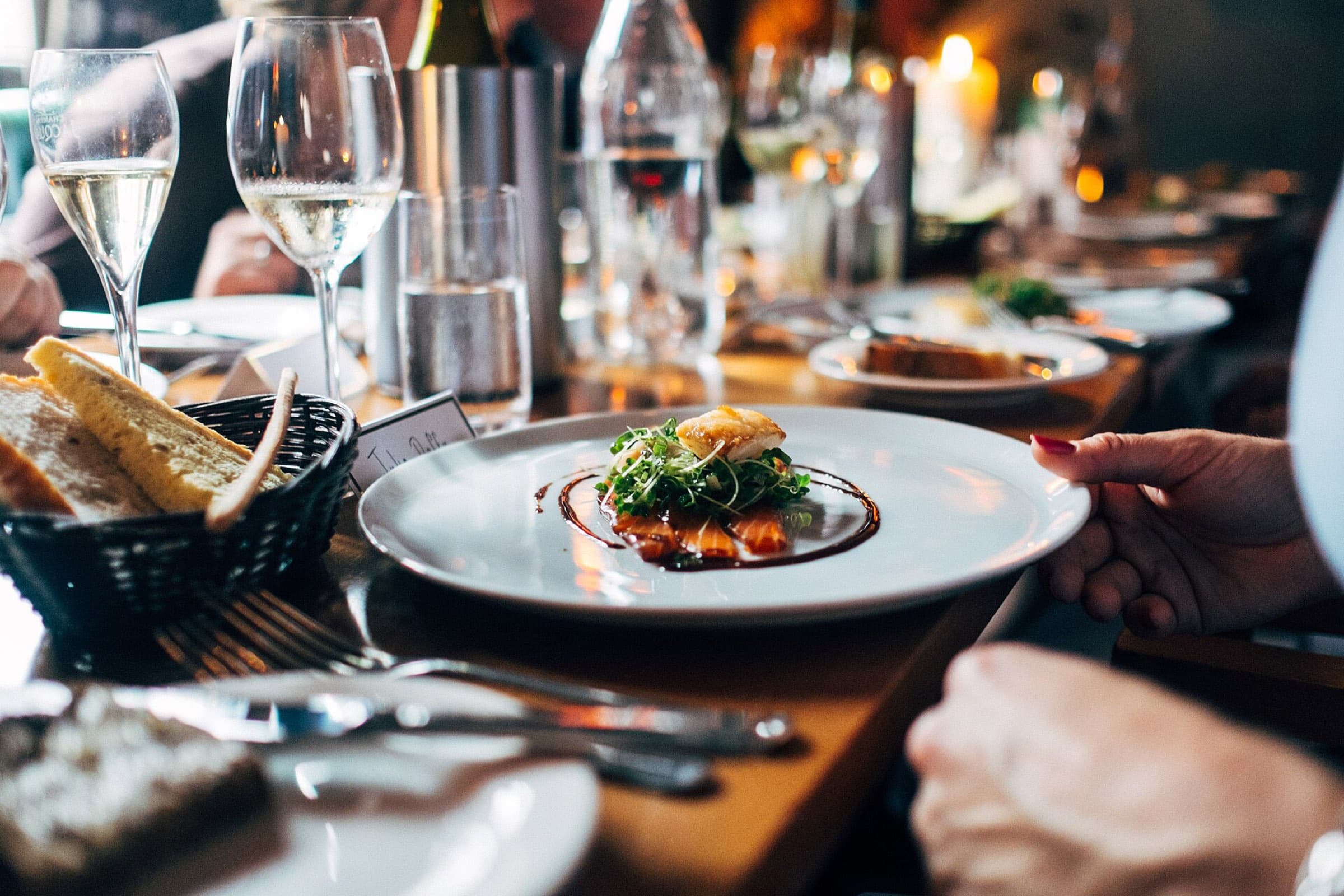 A plated main course and glasses of wine on a busy dinner table