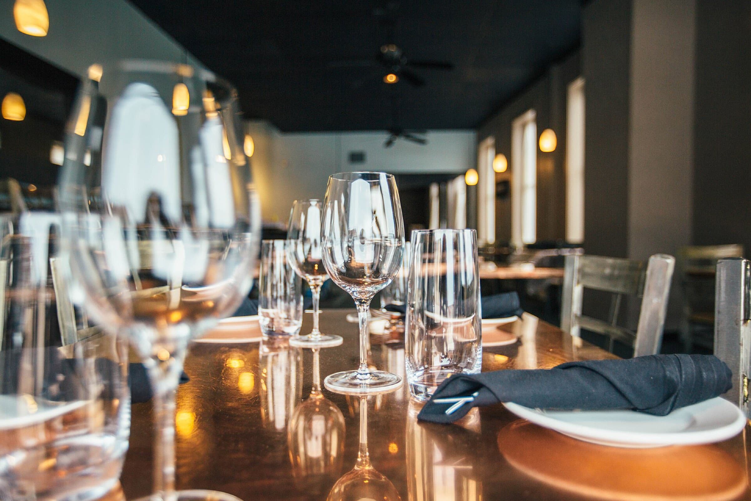A restaurant table set with wine glasses and folded napkins