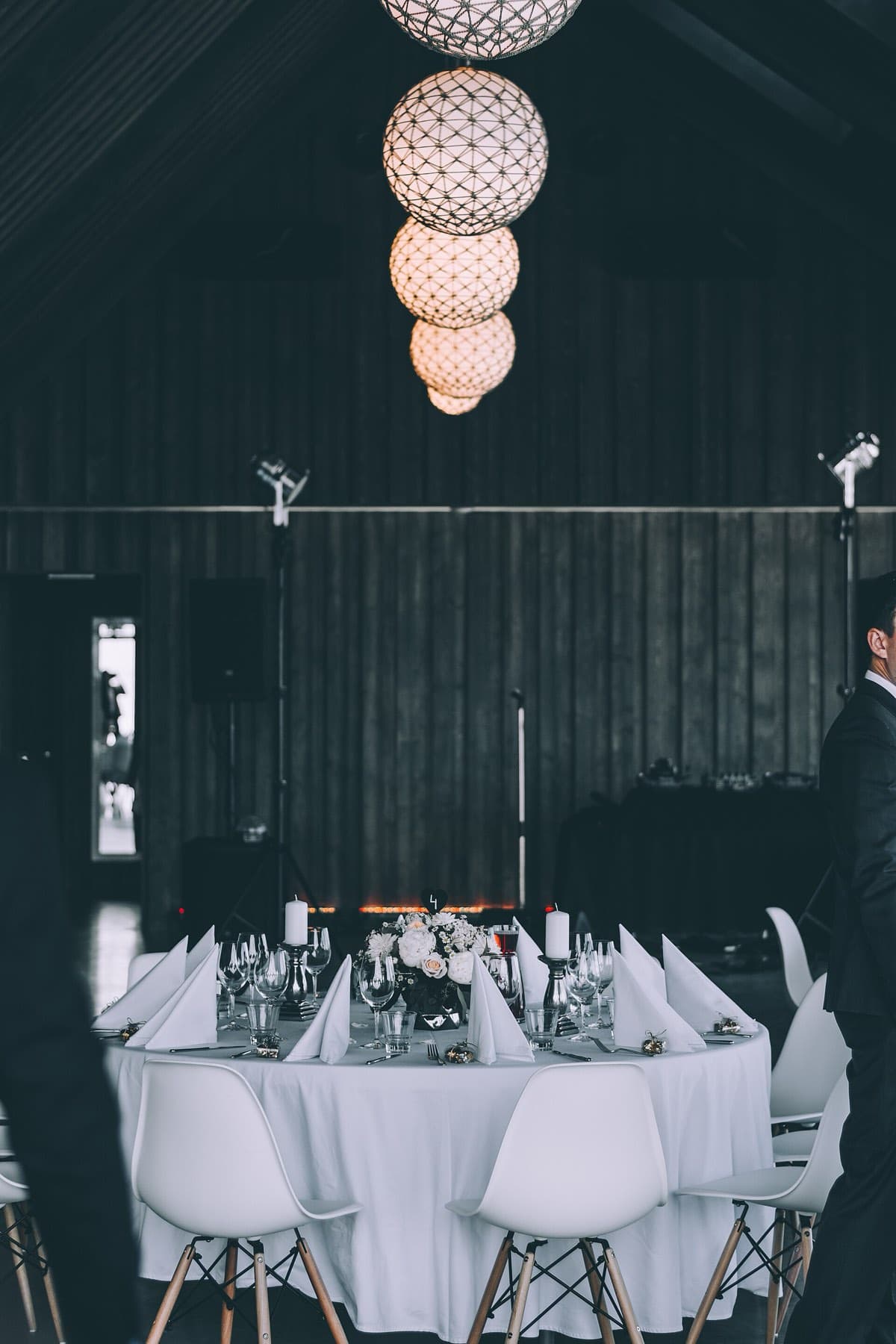 A dark private dining room with a long white table under a pendant lamp