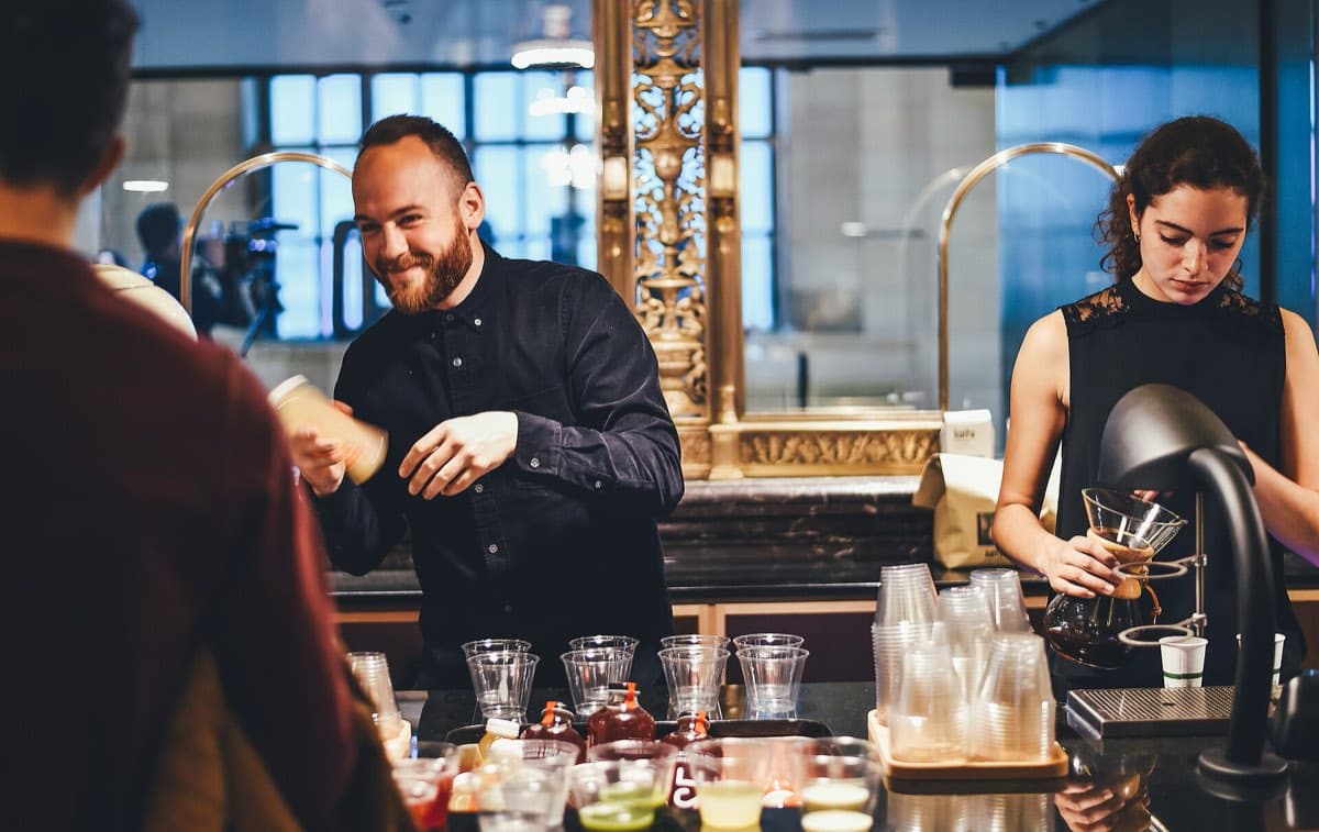 Bartenders smiling while preparing drinks behind a bar